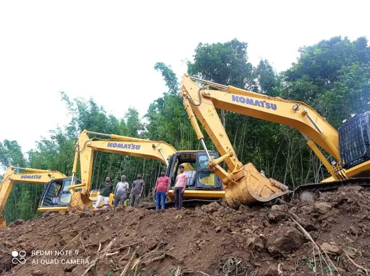 Three Komatsu excavators cutting into a hillside with the SKC crew standing alongside