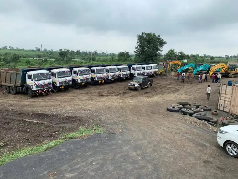 The SKC fleet drawn up on a project yard: seven tippers, a Bolero and four excavators, with the crew alongside